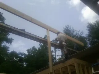 Carpenter setting a ridge beam over a new addition frame — Ice Dam Removal by Roofing Brothers in Dahlgren