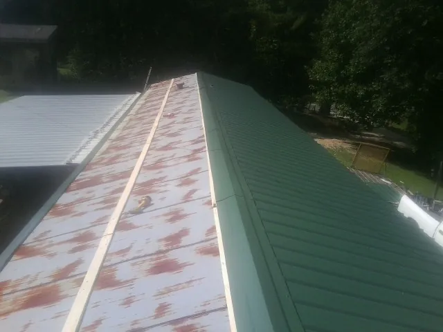 Old rusted panels beside newly installed green metal roofing — Wind Damage Roof Repair by Roofing Brothers in Dahlgren