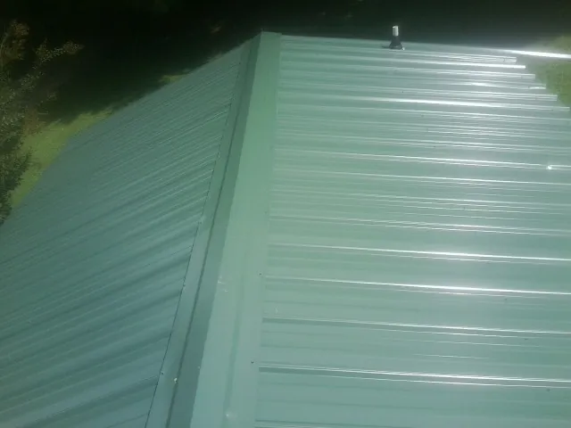 New green metal panels meeting at the ridge of a roof — Flat Roof Repair work by our crew in Dahlgren