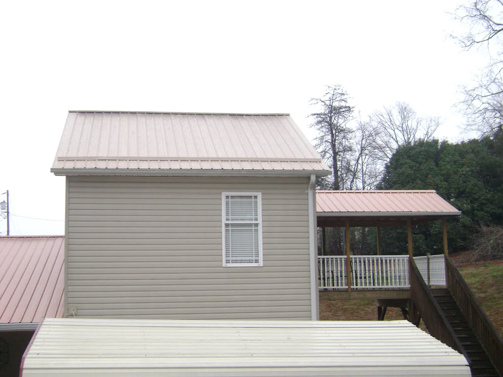 Tan metal roofs on a two story addition and attached porch, from a Roof Replacement job in Dahlgren