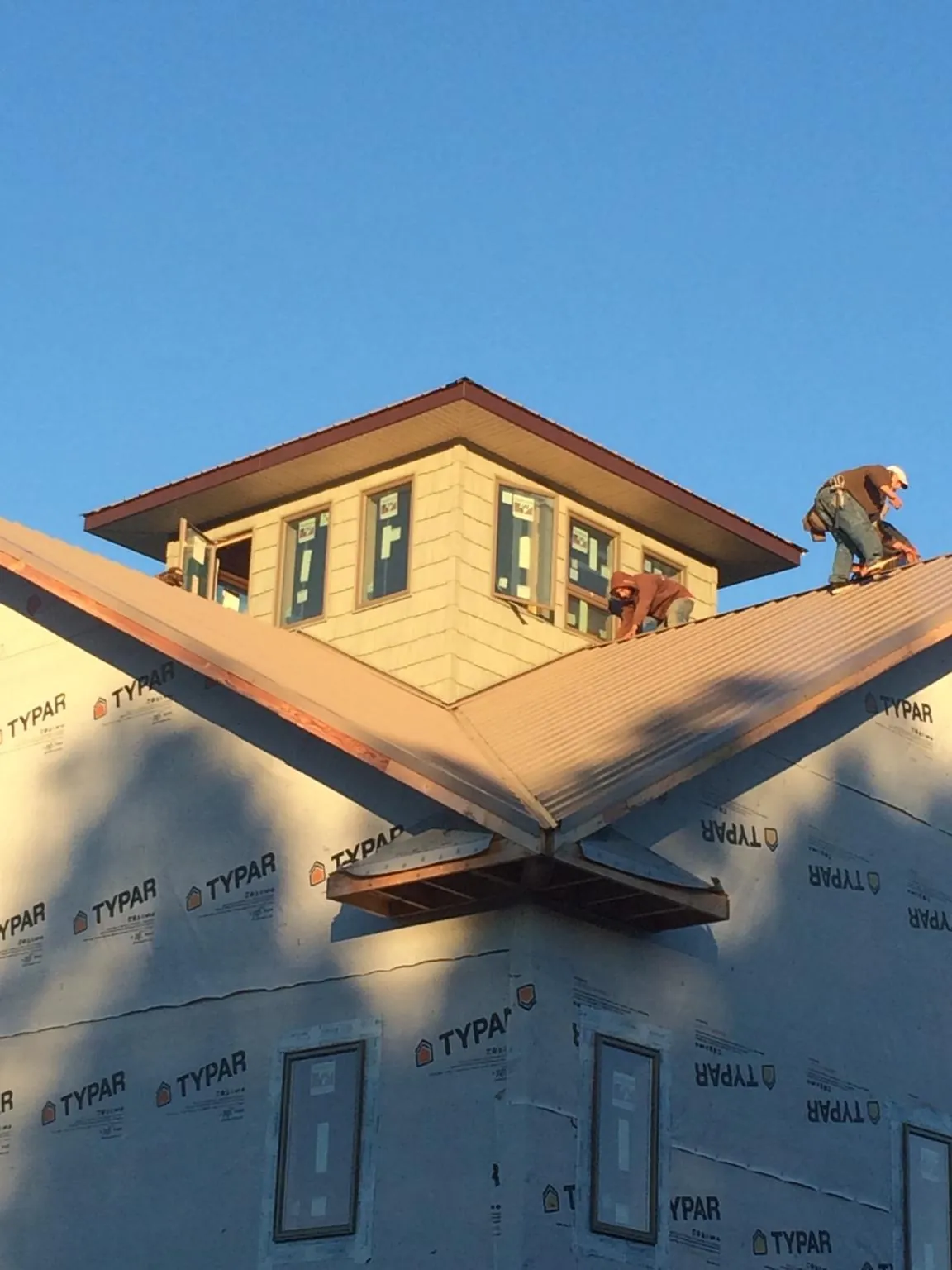 Roofers working around a rooftop cupola on a new metal roof at sunset — Roof Waterproofing in Dahlgren by Roofing Brothers